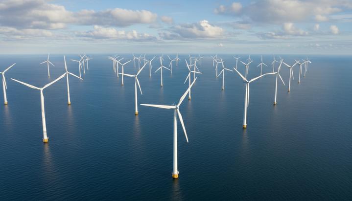 Масштабная морская ветряная электростанция с рядами ветрогенераторов, уходящих за горизонт в открытом море под облачным небом.